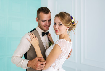 The groom embraces the bride in the bedroom