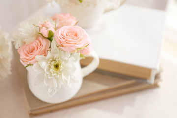 Bouquet of beautiful roses in a cup on a  book