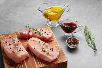 Steaks in marinade on wooden board and grey background