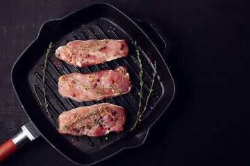 Raw steaks with herb and spices on grill pan