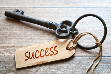 Keys to Success - Concept photo. Old key with paper label on wooden background - Success text.