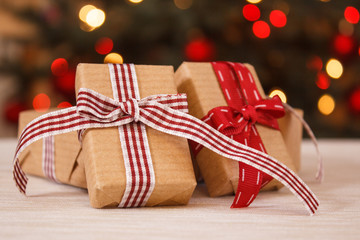 Wrapped gifts and christmas tree with lights in background