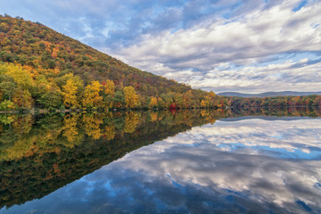 Fototapeta premium Lake at Bear Mountain in New York State in the autumn season during peak foliage with a clear reflection in the water