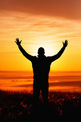 Silhouette of a man praying while facing the sun during Autumn