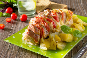 Baked meat with cheese and tomato with baked potatoes on a woode