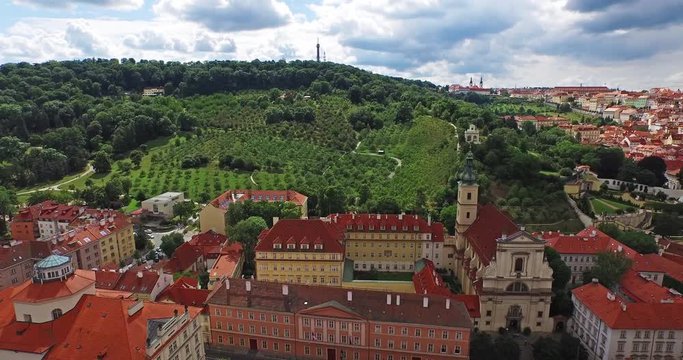 Flying through the old town of Prague, the Czech Republic on a sunny day with dark clouds. Beautiful view of Prague Petrin gardens in 4k.