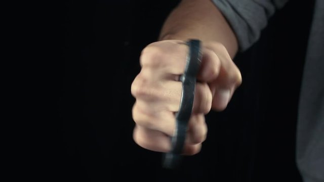 Placing knuckle-duster on the hand male fist with brass knuckles
