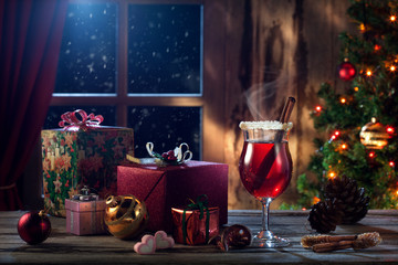 close up view  of glass with mulled wine with gift boxes on color back