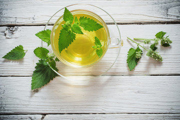 green melissa herbal tea in glass cup on wooden background