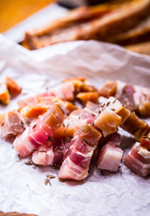 Raw smoked bacon slices on wooden board with cumin and herbs.