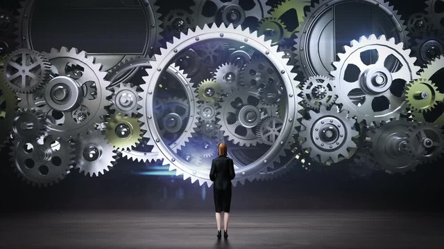 Businesswoman standing big Gear wheels, connecting gear wheels.