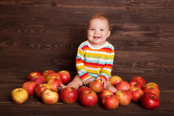 Fototapeta premium Adorable child with red apples on a wooden background 