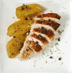baked chicken breast and potato slices on a white plate