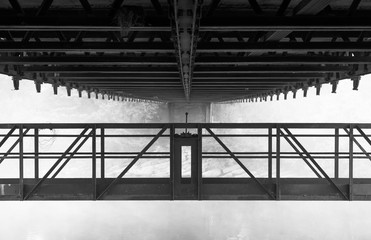 The underside of an old suspension bridge in Lyon during a foggy, autumn day.