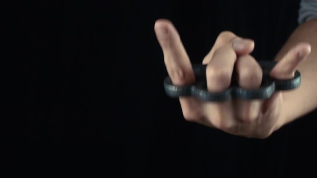 Male hand with knuckle-duster showing devil horn gesture