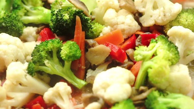 Pouring stir fry sauce over cooking veggies, slow motion