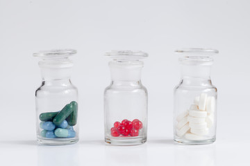 colored pills in glass jars on white background