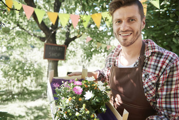 Crate of pretty flowers holding by man .