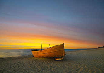 Pomarańczowa łódź rybacka na plaży o zachodzie słońca - obrazy, fototapety, plakaty