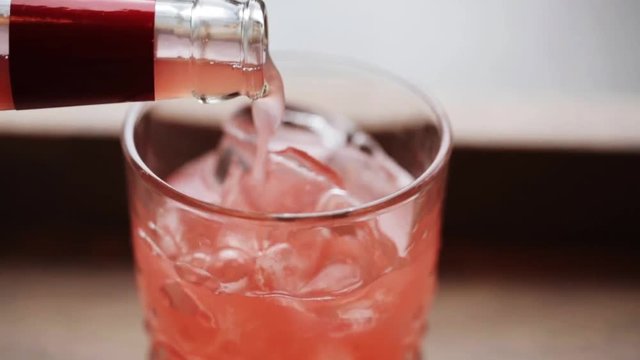 lemonade pouring from bottle to glass with ice
