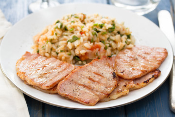 grilled meat with rice on white plate on wooden background
