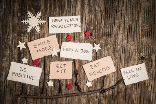 Christmas sleds made of branches and New Year resolutions on rustic wooden background