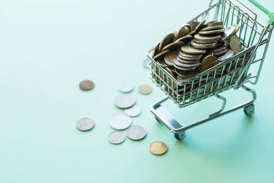 Shopping Cart Full Of Coins Over The Green Background