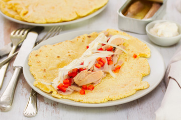 tortilla with fish salad on the plate on wooden background