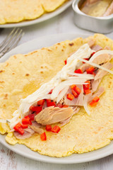tortilla with fish salad on the plate on wooden background
