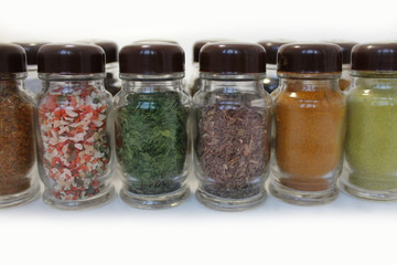 Spices in glass jars on a white background