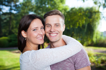 couple happy in park looking at camera