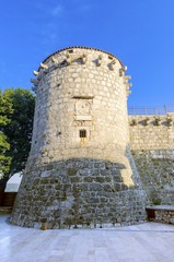 Fototapeta na wymiar The round venetian tower of Frankopan Castle, at Kamplin square in Krk, Croatia - Frankopanski Kastel and plate with a winged Venetian lion, the symbol of St. Mark. Part of the medieval city walls.