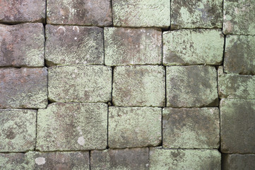 Grunge background of weathered stone blocks with moss discoloration