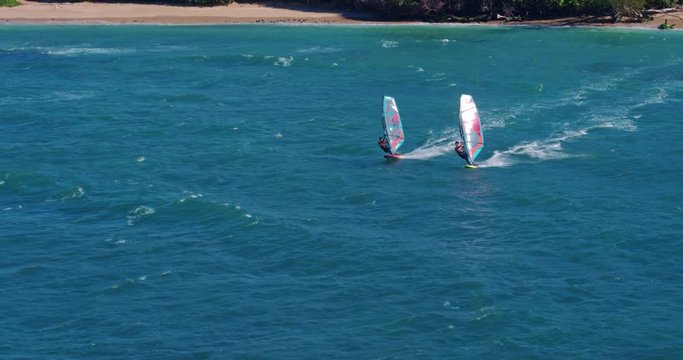 Aerial view of windsurfers gliding across blue ocean, extreme sport