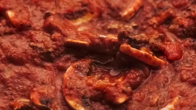Delicious Italian bolognese pasta sauce  cooking with mushrooms and and being mixed with spoon