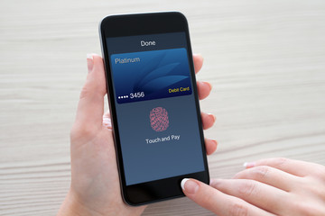 Women hands holding phone with debit card on the screen