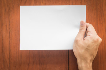 Obraz premium The hand holding a notes paper on wood background
