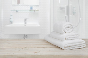 Obraz na płótnie Canvas Blurred bathroom interior background and white spa towels on wood
