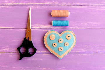 How to create a felt heart crafts. Step. Decorative felt heart with buttons, scissors, thread set, needle on wooden background. Sewing crafts for Valentine's day, wedding, mother's day
