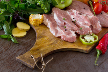 Fresh raw meat pork fillet with vegetables on a concrete backgro