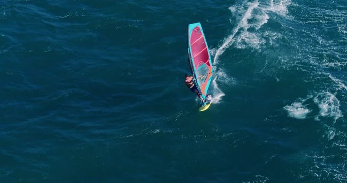 Aerial view of windsurfer gliding across blue ocean, extreme sport