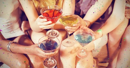 Composite image of girls with cocktails toasting