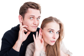 Handsome couple making listening gesture looking amazed