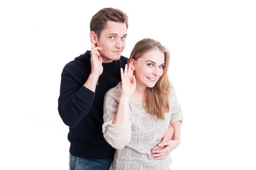Smiling cute couple making listening gesture