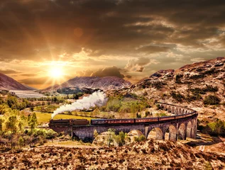 Papier Peint photo Viaduc de Glenfinnan Viaduc ferroviaire de Glenfinnan en Ecosse avec le train à vapeur Jacobite contre le coucher du soleil sur le lac