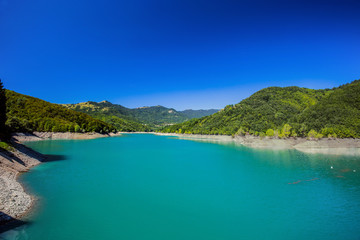 Fototapeta na wymiar The mountain lake with green water under a blue clear sky