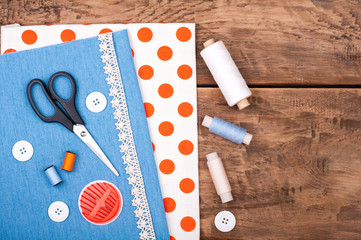 Handmade and sewing background. Fabric for sewing, lace and accessories for needlework on old wooden background. Spool of thread, scissors, buttons, sewing supplies. Set for needlework top view