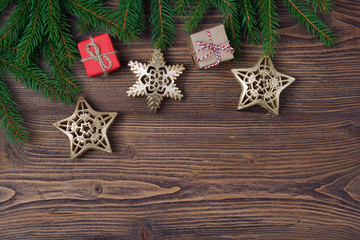 Christmas background with fir frame, presents, golden stars and snowflakes, wooden background