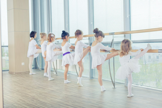 Group of seven little ballerinas standing in row and practicing 