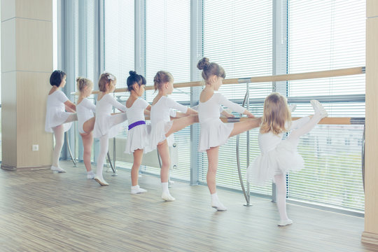 Group of seven little ballerinas standing in row and practicing 